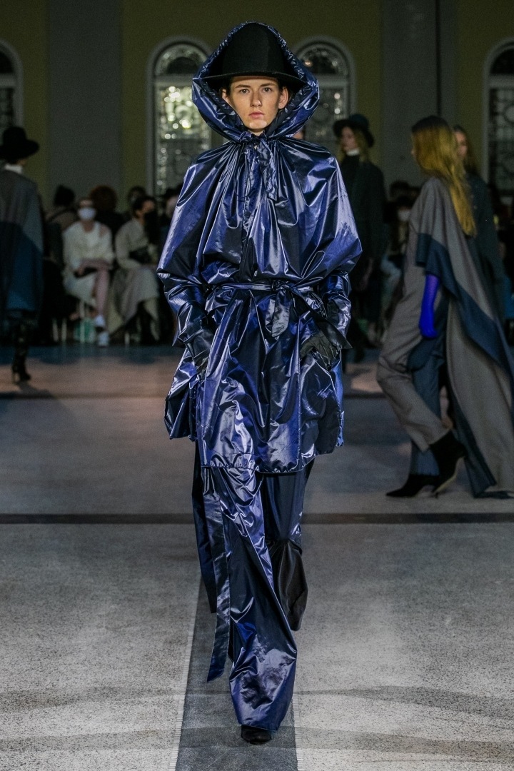 Žena v tmavě modrém outfitu s kapucí od Jakuba Polanky 