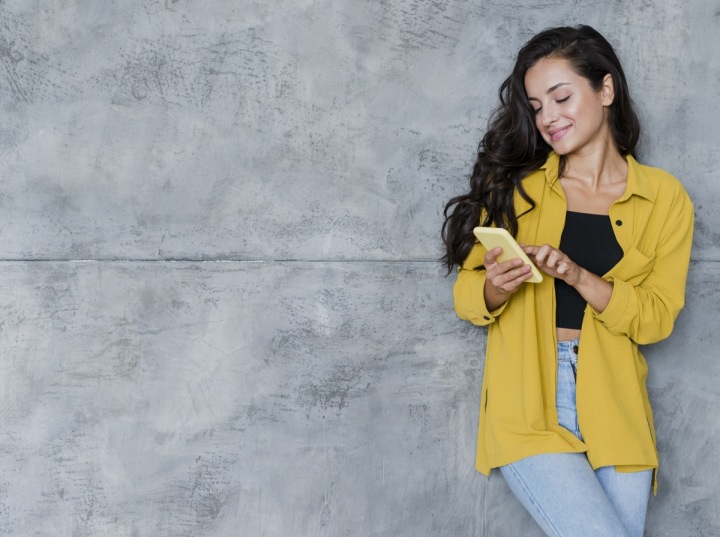 Žena ve žluté bundě používá svůj smartphone Žena ve žluté bundě používá svůj smartphone