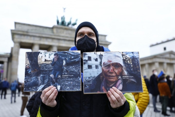 Demonstrant drží snímky pořízené v Charkově během protestu proti ruskému vojenskému zásahu.