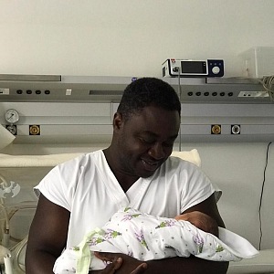 Patrice drží čerstvě narozené miminko. 