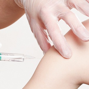 Očkování - rameno očkovaného a ruka s injekcí