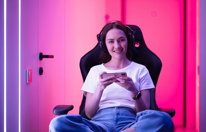 Dívka v herním křesle hraje hru na mobilu