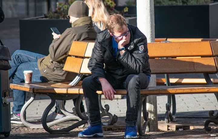 Smutný muž sedící na lavičce.