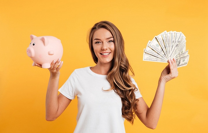 Mladá dívka s penězi a kasičkou v ruce