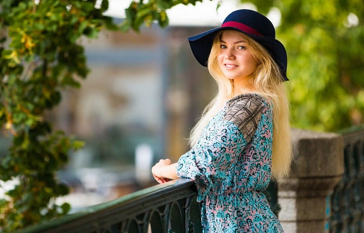 Žena v klobouku opřená o zábradlí