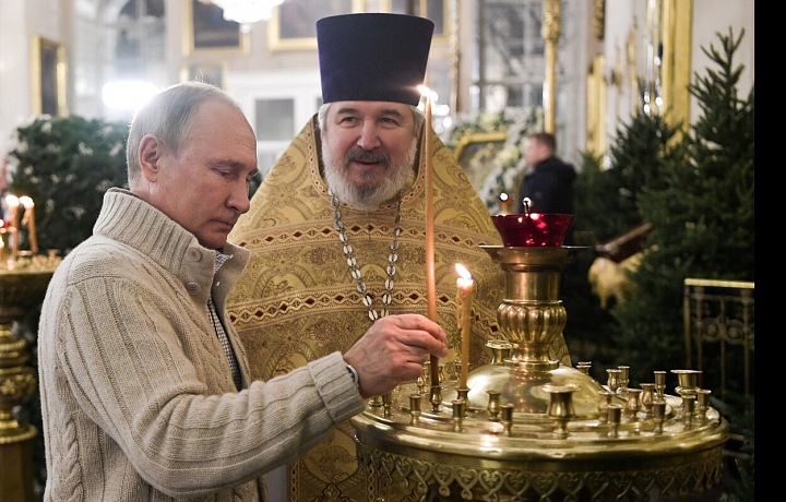  Ruský prezident Vladimír Putin a vrchní kněz katedrály Nikolaj Bryndin zapalují svíčky