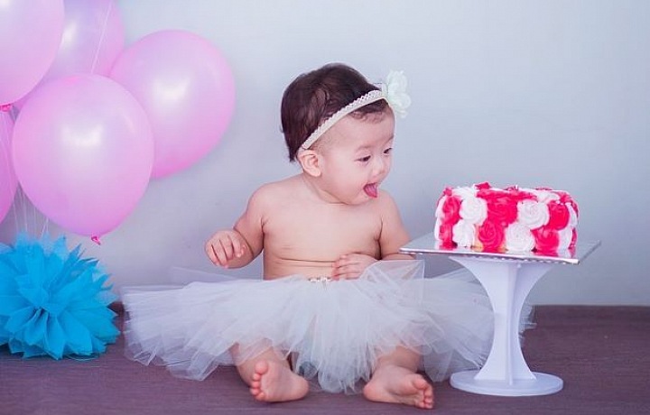 Miminko při oslavě narozenin s balonky a dortem. 