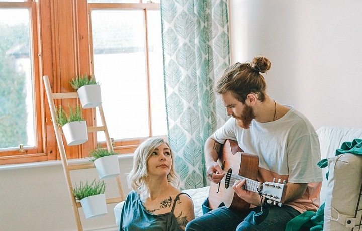 Mladý pár, muž hrající na kytaru.