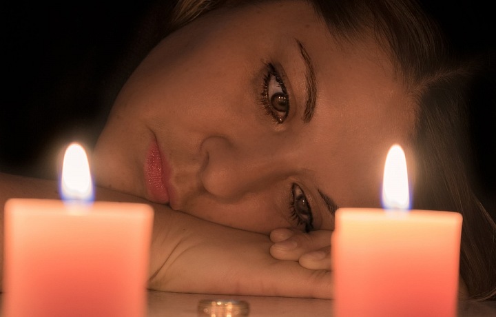 Žena při svíčkách vzpomínající na svého zesnulého manžela