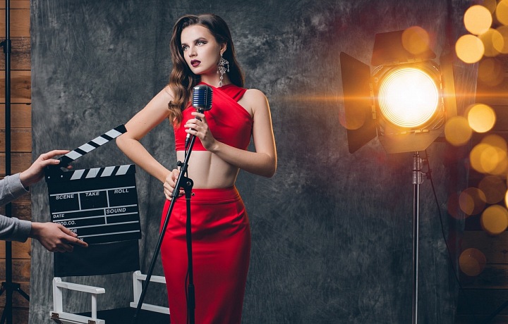 Mladá stylová žena stojící před filmovou "klapkou"