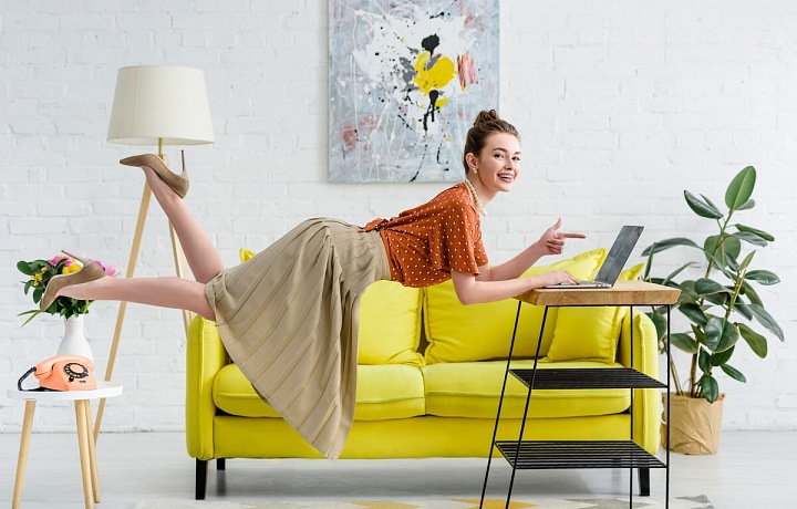 Žena u počítače a v pozadí žlutá pohovka