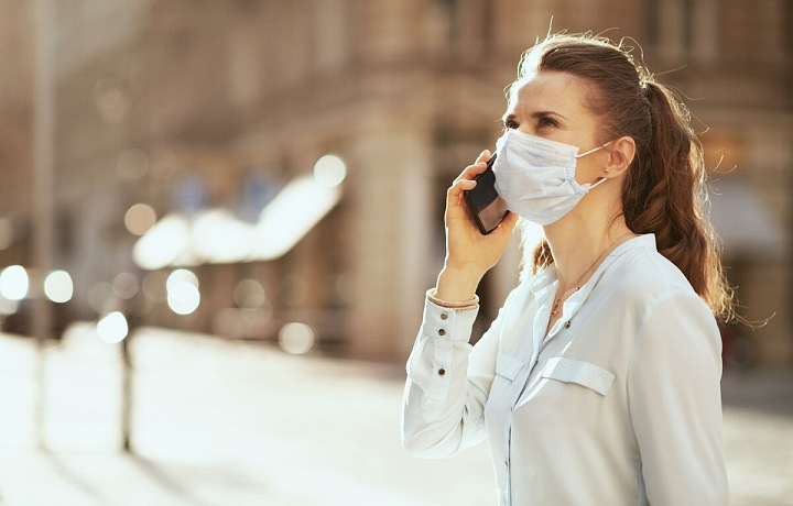 Žena s rouškou telefonuje na ulici