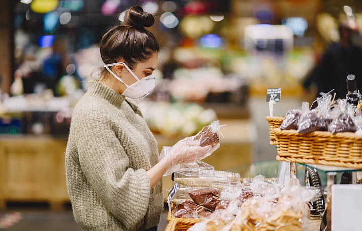 Žena v roušce nakupuje.